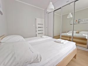 斯维诺乌伊希切Baltic Home Sienkiewicza 5的一间白色卧室,配有两张床和镜子