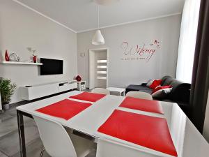 斯维诺乌伊希切Baltic Home Sienkiewicza 5的客厅配有带红色靠垫的白色桌子