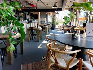 克诺克－海斯特Lakeside Paradise Sport Hostel的一间设有桌椅的餐厅,种植了植物