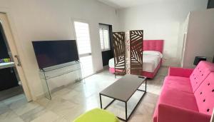 塞维利亚Ritual Alameda Suites的客厅配有粉红色的沙发和电视