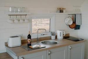 StrathyStrathy Bay Pods的带水槽的厨房台面和一瓶葡萄酒