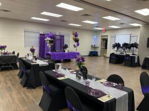奥卡拉Howard Johnson by Wyndham Ocala FL I-75的一间设有桌椅的客房,配有紫色和紫色的鲜花