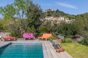 巴古尔Flateli Begur Cabanya的一座带五颜六色椅子的游泳池,位于一座房子旁边