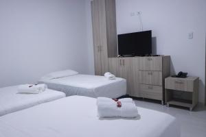 CamaronesOMA HOTEL LA GUAJIRA的一间酒店客房,设有三张床和一台平面电视