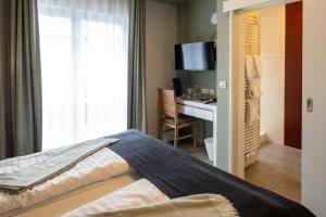 耶弗尔Stadthotel Jever的一间卧室配有一张床和一张书桌及电视