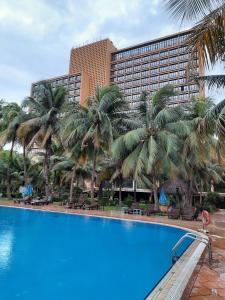 巴马科GRANADA l'Amitié的一座棕榈树环绕的大酒店,位于游泳池前
