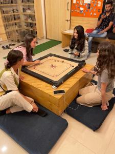 孟买Nap Manor Hostels的一群女孩坐在桌子旁玩游戏