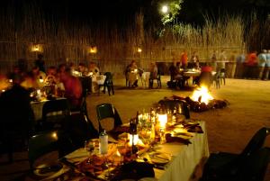 MbabatTimbavati Safari Lodge的一群人晚上坐在餐馆的桌子上
