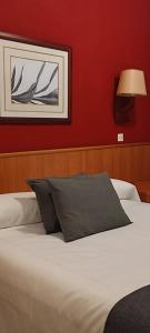 布拉内斯里贾纳旅馆的卧室内的一张床位,卧室设有红色的墙壁