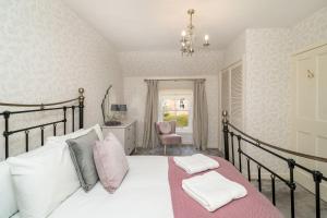 基里缪尔Thrums Cottage的一间卧室配有带白色床单和粉红色枕头的床。