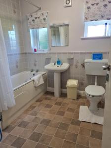 斯卡伯勒Woodpeckers Cottage的浴室配有盥洗盆、卫生间、浴缸和盥洗盆。