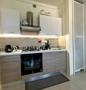 巴多利诺Elena Apartment Residence的厨房配有白色橱柜和炉灶烤箱。
