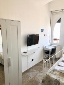 安科纳B&B Il Poeta sul Mare的白色的客房设有电视和带电脑的书桌