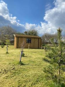 汤顿Lakeside Lodge的一座小木结构建筑,位于田野上,有树