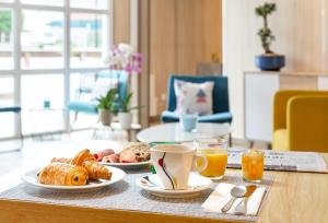 巴朗坦BRIT Hotel Rouen Nord - Barentin的一张桌子,上面放着两盘早餐食品和橙汁