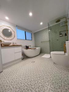 阿尔丁格Maunder Cottage的浴室配有2个盥洗盆、浴缸和淋浴。