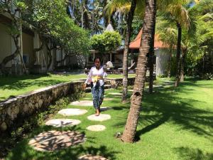 珀尼达岛Akatara Hotel的走在花园小径上的女人