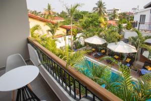 马德望Cambana La Rivière Hotel的享有游泳池和棕榈树景致的阳台