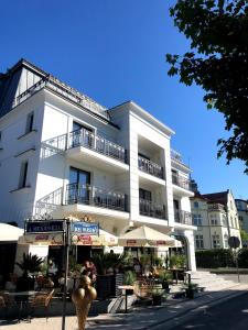米兹多洛杰Luxury Apartments in Residence Maritime的前面有桌子和遮阳伞的白色建筑