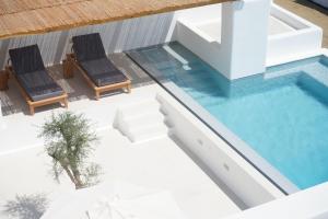 圣乔治Alio Naxos Luxury Suites的一个带两把椅子的游泳池和一个游泳池