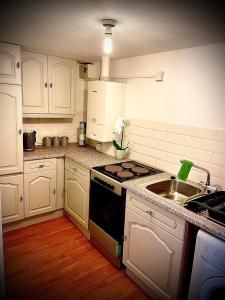 南米尔福德T-post guest house的厨房配有白色橱柜和炉灶烤箱。