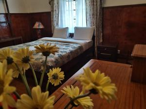 努沃勒埃利耶特列文酒店的一间卧室配有一张床和一张黄色花卉桌子