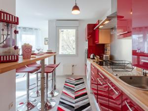 维勒班LE STELLA - HYPERCENTRE GARAGE GRATUIT WiFi NETFLIX AMAZON PRIME PROCHE PARC TETE D'OR的一间厨房,配有红色橱柜和红色吧台凳