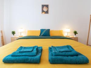 维勒班LE STELLA - HYPERCENTRE GARAGE GRATUIT WiFi NETFLIX AMAZON PRIME PROCHE PARC TETE D'OR的一张黄色的大床,上面有蓝色的毛巾