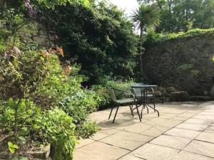 赫尔斯顿Woodland cottage in Cornwall with walled garden的花园内带桌椅的庭院