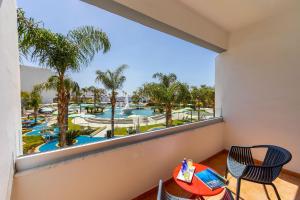 阿依纳帕Faros Hotel Ayia Napa的享有游泳池和棕榈树景致的阳台