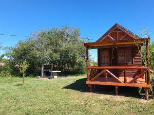 瓜莱瓜伊Chacra Mandala的田野上的一个小木房子,有长凳