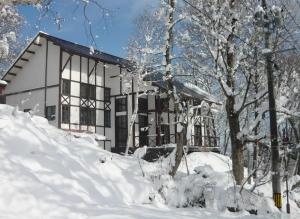 妙高妙高山林小屋的一座房子,前面有树木,被雪覆盖着