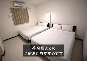 石垣岛KARCHIBE ISHIGAKI的小型客房内的两张床,墙上写着书