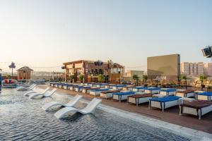 迪拜Avani Ibn Battuta Dubai Hotel的一个带桌椅的度假村游泳池