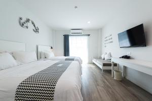 柴老海滩佩吉湾度假酒店的一间白色卧室,配有两张床和一台平面电视