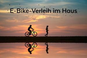 伊尔米茨KRACHER Ferienhaus Landhaus No 1的骑着自行车的人与骑着自行车的人在日落时分