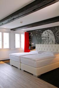 布伦瑞克豪斯楚汉萨同盟酒店的卧室配有一张白色大床,墙上挂着狮子