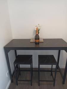 比勒瑞卡Froden Court的一张黑桌,上面有一瓶葡萄酒和凳子