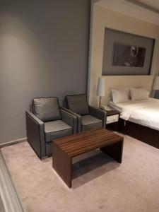 利雅德Taleen Hotel的酒店客房配有一张床、一张沙发和椅子。