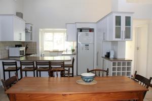 普利登堡湾T1 Goose Valley with Sea View的厨房配有木桌、椅子和冰箱