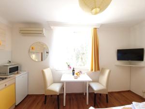 杜布罗夫尼克Apartments Dabar的厨房配有白色的桌椅和窗户。