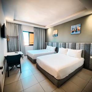达赫拉Hotel Dakhla Ville的酒店客房配有两张床和一张书桌