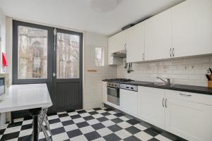 多德雷赫特Voorstraat-Straatzicht Boven的厨房配有白色橱柜和 ⁇ 格地板