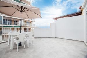 埃尔佩雷略Ático con espectacular terraza y vistas al mar的庭院配有桌椅和遮阳伞。