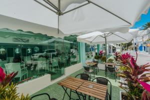 蓬塔卡纳Green Coast Beach Hotel的庭院设有木凳、桌子和遮阳伞。