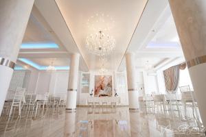 皮亚特拉-尼亚姆茨Hotel-Restaurant Ayan Piatra Neamt的一间设有白色桌椅和吊灯的客房