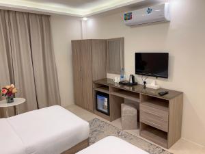 瓦迪穆萨Beit Alshabaan Inn的酒店客房配有一张床和一张书桌及一台电视