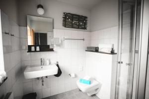 博尔库姆Pension Mai-Scholle的白色的浴室设有水槽和卫生间。