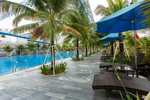 Dĩ AnHoang Hung Hotel的一个带游泳池、棕榈树和椅子的度假酒店