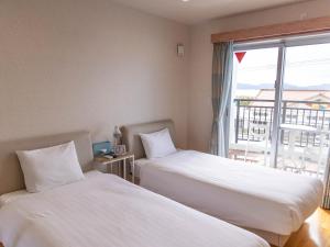 名户YANBARU STAY ちゅら宿的配有窗户的酒店客房内的两张床